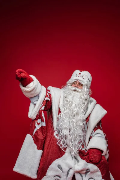 Kıdemli Noel Baba, gri sakallı, kırmızı arka planda, fotokopi aletiyle el işaretli. — Stok fotoğraf