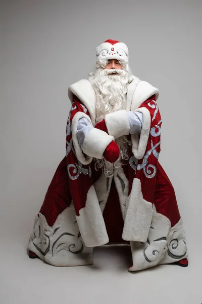 Cool gray haired with long beard Santa Claus in red clothes posing on gray studio background — Stock Photo, Image