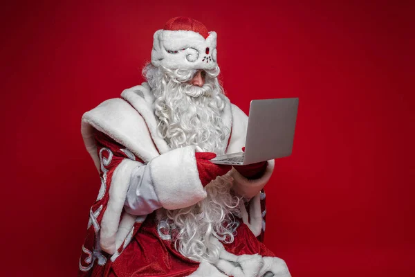 Santa usando laptop no fundo vermelho. — Fotografia de Stock