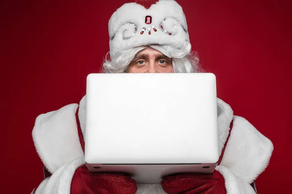 Santa com laptop olhando para a câmera sobre ele. — Fotografia de Stock