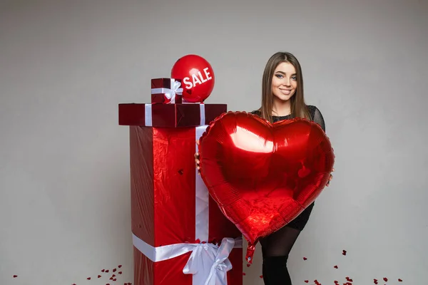 발렌틴 데이 연휴 세일, 심장 모양을 하고 복제품 공간이 있는 젊은 여자 아이, 회색 배경에 빨간 선물 — 스톡 사진
