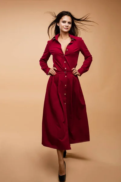 Elegante jovem morena modelo feminina em vestido vermelho posando andando no fundo do estúdio com espaço de cópia para anúncio — Fotografia de Stock