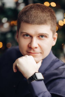 Kısa siyah saçlı güçlü beyaz adam kameraya bakıyor.