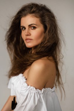 Güçlü yüzü ve makyajı olan yakışıklı kadın kameraya bakıyor.