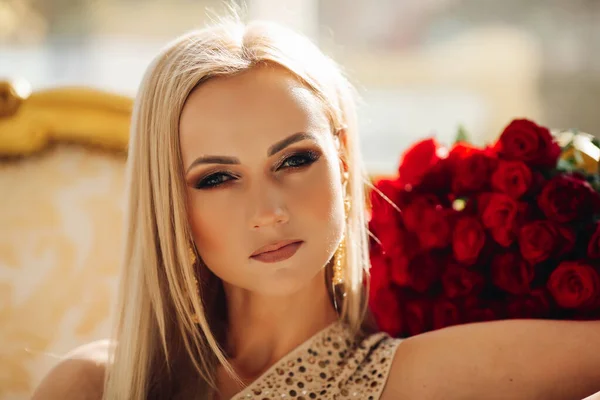 Impresionante rubia con maquillaje y rosas en el fondo. — Foto de Stock