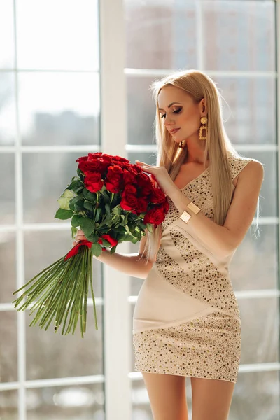 Красивая блондинка в платье смотрит на цветы — стоковое фото