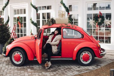 Genç kız kışın güzel kırmızı bir arabada oturur.