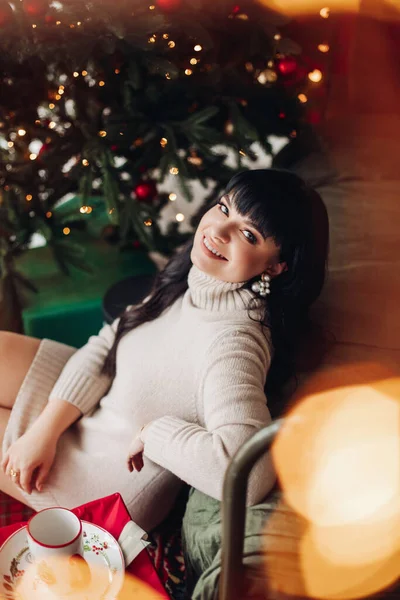 Glad kvinna vid en julgran som vänder sitt leende ansikte mot kameran — Stockfoto