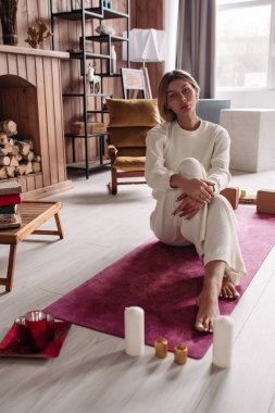 Beyaz elbiseli güzel bir kadın, paspasın etrafında mumlar..