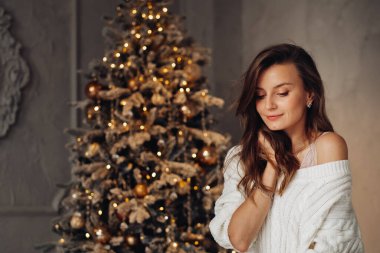 Göz kamaştırıcı genç bayan ışıl ışıl Noel ağacının yanında poz veriyor