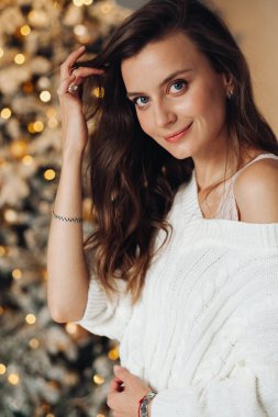 Süslü Noel ağacının yanında poz veren beyaz kazaklı güzel bayan.