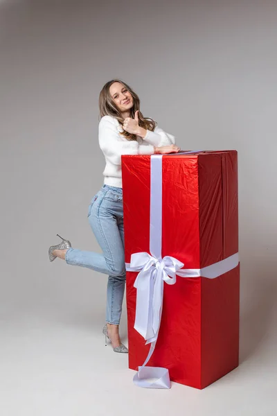 아름다운 여성 모델 이 크리스마스 선물로 큰 빨간 상자를 들고 카메라 앞에 나타난다. — 스톡 사진