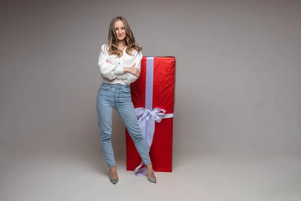Chica joven bastante en forma con gran regalo rojo en fondo gris estudio con espacio de copia para la publicidad de vacaciones — Foto de Stock