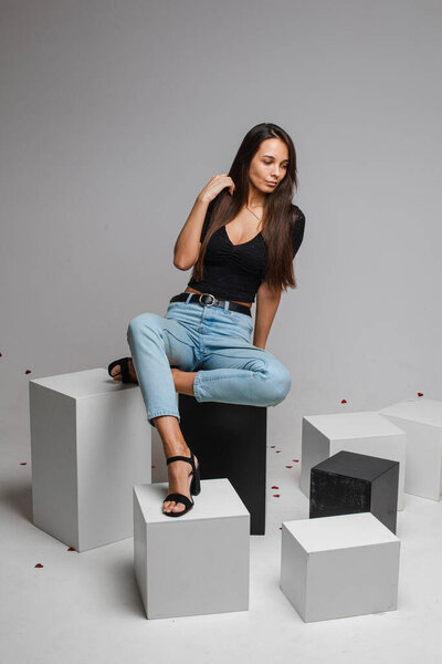 female model in re skirt and denim jeans poses for the camera on black and white cubes