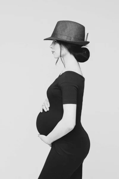 Vacker gravid kvinna med hatt röra hennes mage och titta åt sidan — Stockfoto