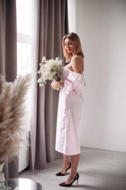 Orta sarı saçlı, beyaz çiçeklere bakan yakışıklı bir kadın.