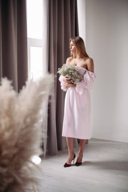 Çiçeklerle poz veren genç bayan.