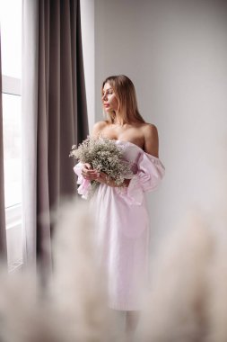 Çiçeklerle poz veren genç bayan.