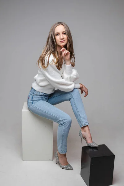 Attractive blonde woman in sweater and jeans in studio. — Fotografia de Stock