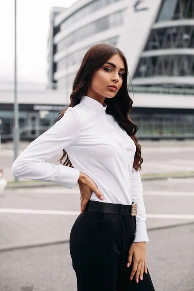 Krásná brunetka pózující na pozadí moderní budovy — Stock fotografie