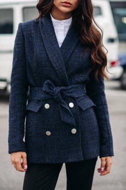 Kalın kumaştan yapılmış, ince bir kızın beyaz düğmeleri ve terzisiyle süslenmiş güzel bir siyah takımın parçası.