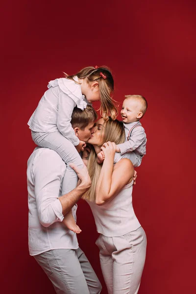 Make och maka kysser med barn på axlarna. — Stockfoto