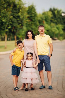 Dört kişilik mutlu bir aile yazın birlikte parkta yürüyor.