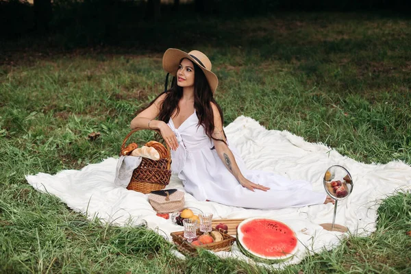 Porträt eines jungen schönen Mädchens mit sogar weißen Zähnen, einem schönen Lächeln im Strohhut und langem weißen Kleid beim Picknick im Garten — Stockfoto