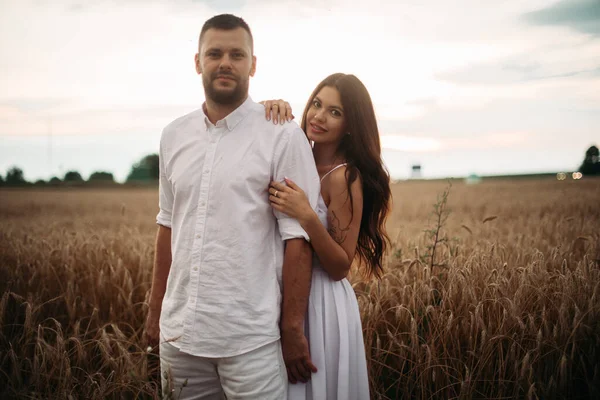 Mujer bastante caucásica con el pelo largo y ondulado oscuro en abrazos de vestido blanco con hermoso hombre en camiseta blanca y pantalones cortos — Foto de Stock