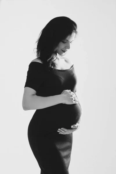 美しい若い妊娠中の女性は、スタジオでポーズ腹を受け入れます,黒と白の写真.幸せな妊娠・出産 — ストック写真