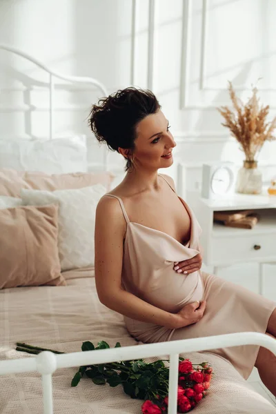 Приваблива вагітна жінка позує на камеру на своєму ліжку — стокове фото