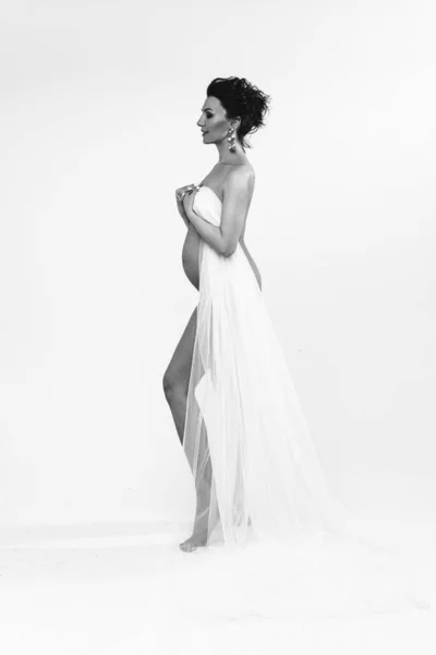 黒と白の魅力的な妊婦の写真白い布を持ってカメラの脇に立って — ストック写真