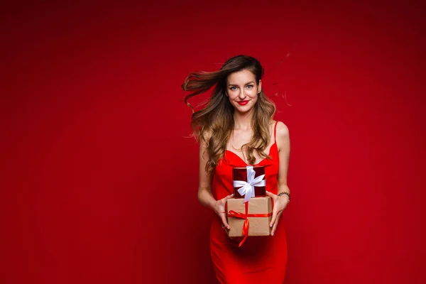 Modelo de moda feminina bonita em vestido vermelho detém um monte de pequenas caixas com presentes e alegrias — Fotografia de Stock