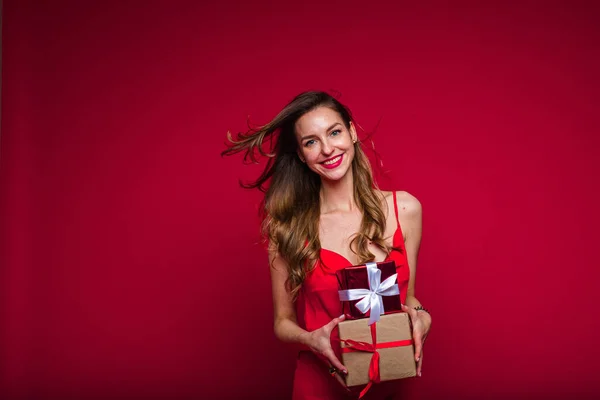 Όμορφο γυναικείο μοντέλο μόδας σε κόκκινο φόρεμα κατέχει πολλά μικρά κουτιά με δώρα και χαρές — Φωτογραφία Αρχείου
