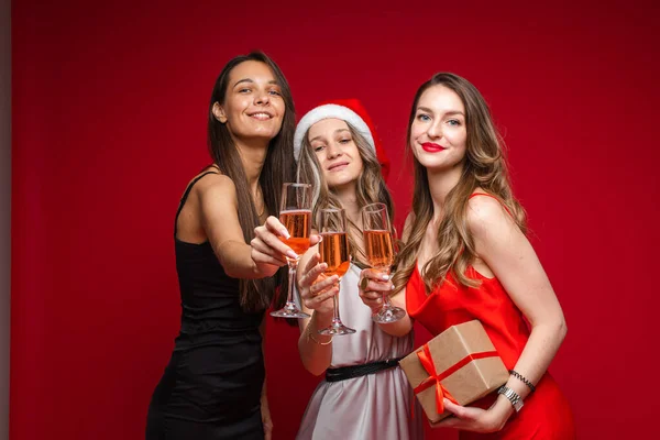 Szczęśliwe młode dziewczyny z prezentem i szampanem świętując wakacje razem na imprezie na czerwonym tle, przestrzeń do kopiowania — Zdjęcie stockowe