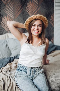 Güzel kız yatağında oturur, rahatlar ve hayattan zevk alır.