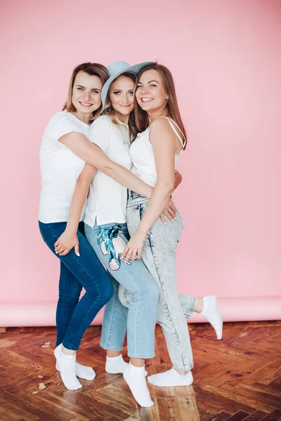 Trzy kobiety w letnich ciuchach mają dużo zabawy na przyjęciu urodzinowym, zdjęcie odizolowane na różowym tle — Zdjęcie stockowe