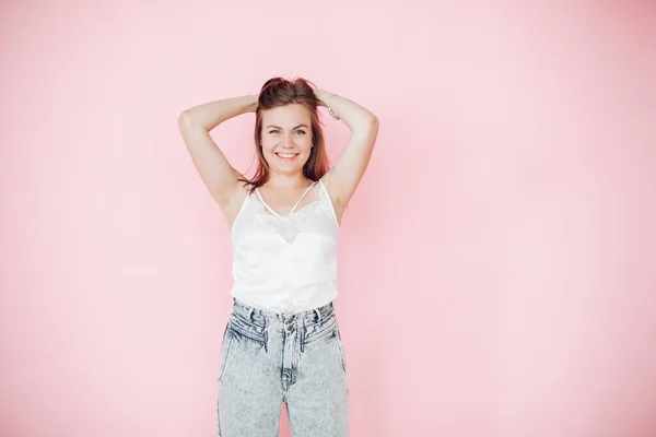 Rapariga atraente em roupas de verão deu muita diversão e brinca com o cabelo, imagem isolada no fundo rosa — Fotografia de Stock