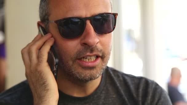 Чоловік у кав'ярні розмовляє по телефону — стокове відео