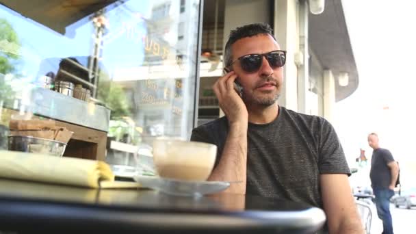 Man i ett café som talar i telefon — Stockvideo