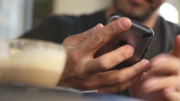 El hombre utiliza el teléfono inteligente en un café — Vídeos de Stock