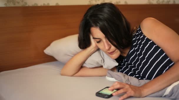 Γυναίκα γέλια ενώ χρησιμοποιείτε κινητό τηλέφωνο στο κρεβάτι — Αρχείο Βίντεο