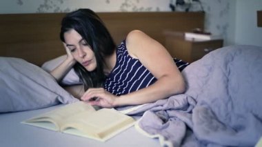 Çekici kadın yatakta bir kitap okuma