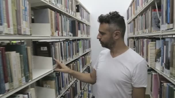 Student söker böcker på biblioteket — Stockvideo