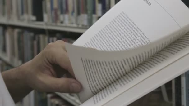 Студент читает книгу в библиотеке — стоковое видео
