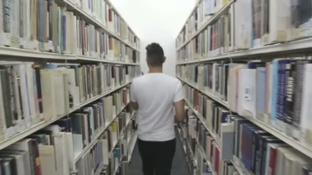 Student söker böcker på biblioteket — Stockvideo