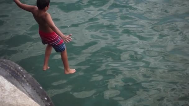 Маленький ребенок прыгает в воду медленным ходом — стоковое видео