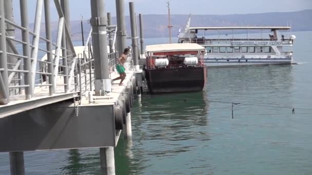 Teen jump off a bridge to dive into the water — Stock Video