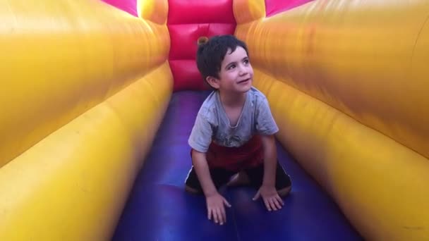 Niño que se divierte en el castillo hinchable inflable — Vídeos de Stock