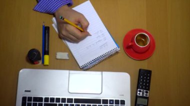 Üstten Görünüm bir adam yazmak üstünde okul sırası ile laptop ve defter